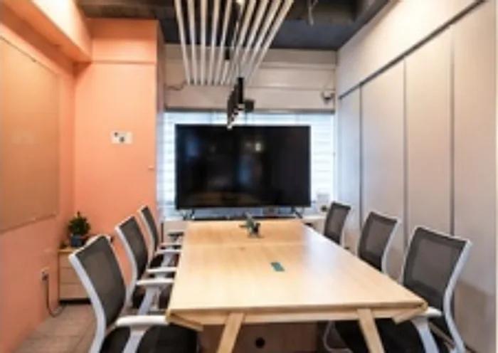 Meeting room with a long wooden table, mesh chairs and a wall-mounted screen