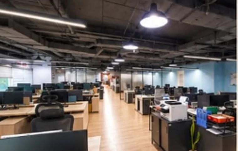 Open-plan office floor with rows of desks, monitors and pendant lights